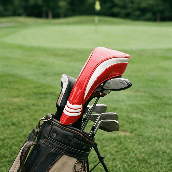 Golf clubs in a bag with a red and white club head cover on a golf course background